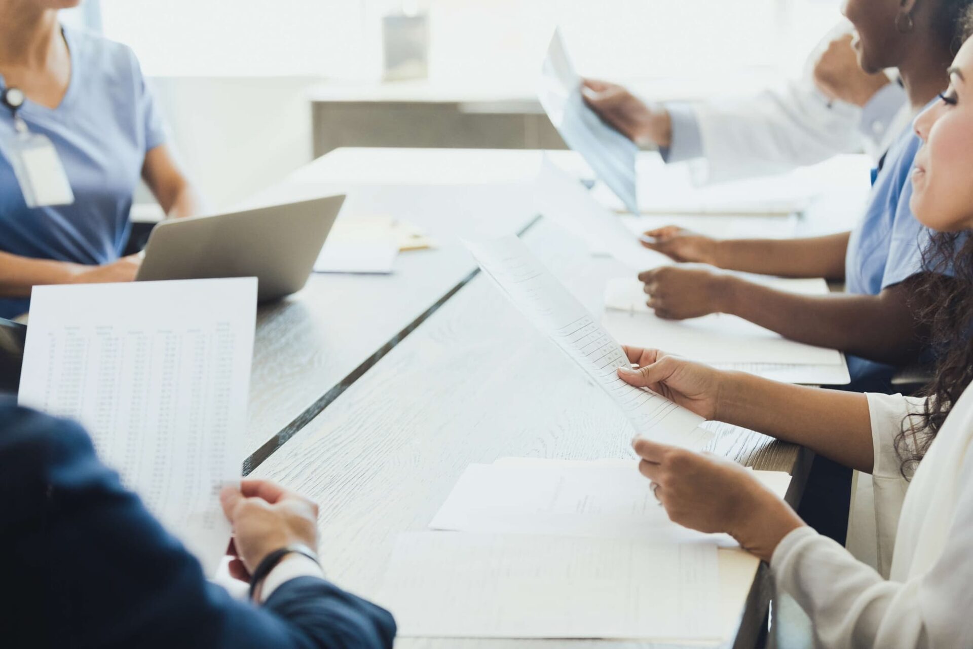 A diverse group of individuals sitting around a table, engaged in discussion and reviewing documents.